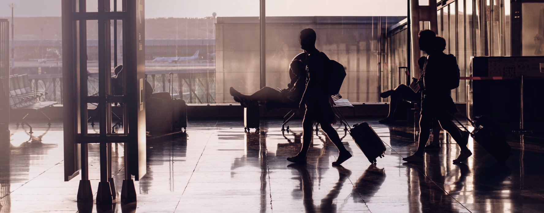 Travellers with suitcases silhouetted in an airport terminal