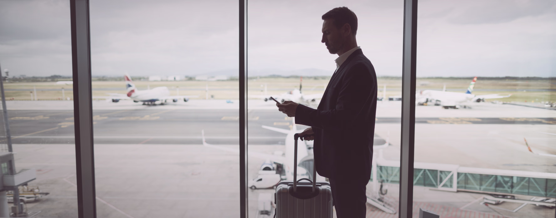 Pilot with a suitcase looking out at aircraft on the apron