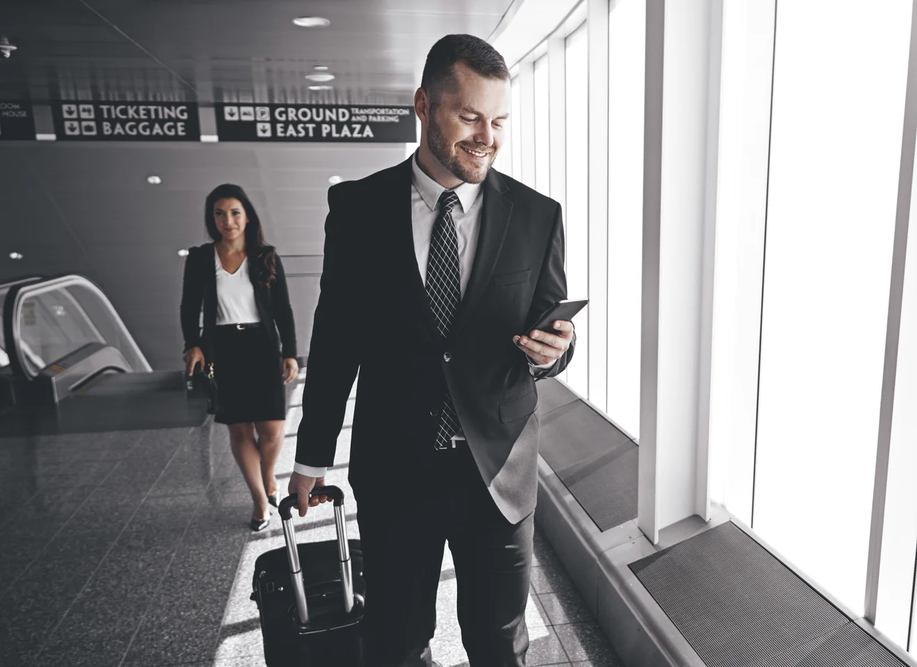 Airline manager checking flight operations on his phone while walking through an airport terminal