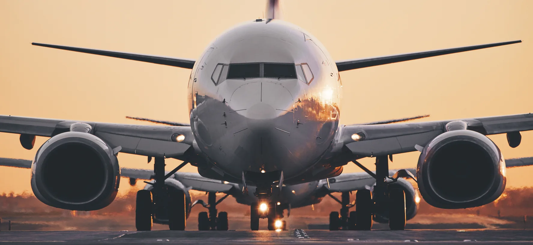 Passenger jet lined up on the runway at sunrise, viewed head-on