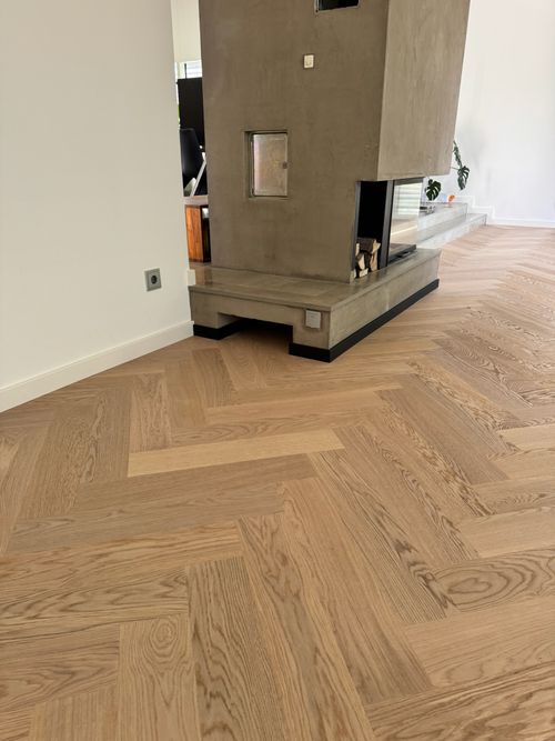 Professionelle Parkettschleifmaschine von Damian Parkett & Boden auf einem fertig geschliffenen, dunkelbraunen Fischgrät-Parkett.