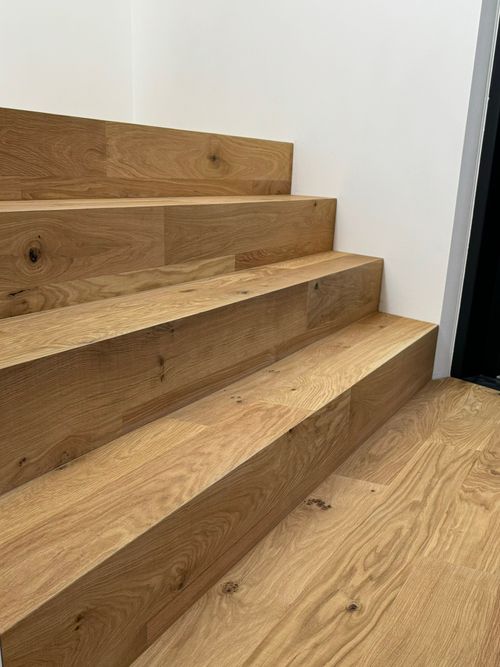 Moderne, geschlossene Treppe mit breiten Eichenholzstufen (oder Massivholzstufen), Referenz von Damian Parkett & Boden.