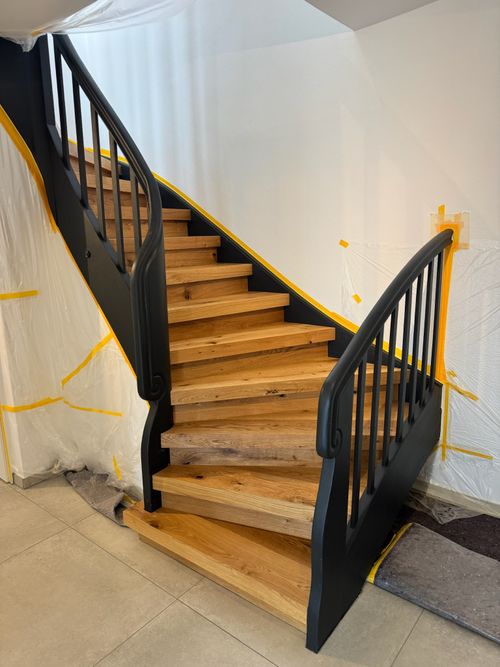 Klassische Holztreppe mit schwarzem Geländer, deren Stufen von Damian Parkett & Boden saniert wurden