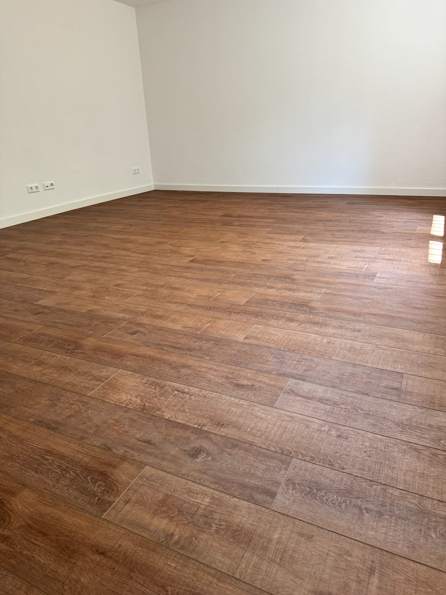 Moderner, dunkler Parkettboden (Dielen-Optik) von Damian Parkett & Boden, verlegt in einem klaren Raum.