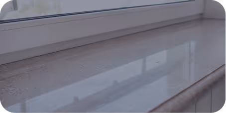 Nahaufnahme einer sauberen, glänzenden Fensterbank aus Stein mit Fenster darüber.