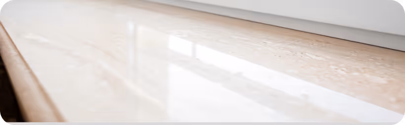 Nahaufnahme einer glatten, glänzenden Stein- oder Marmoroberfläche mit Lichtreflexionen.