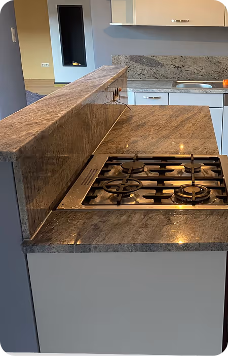 Moderne Küche mit grauer Marmorarbeitsplatte und eingebautem Gaskochfeld mit vier Brennern.