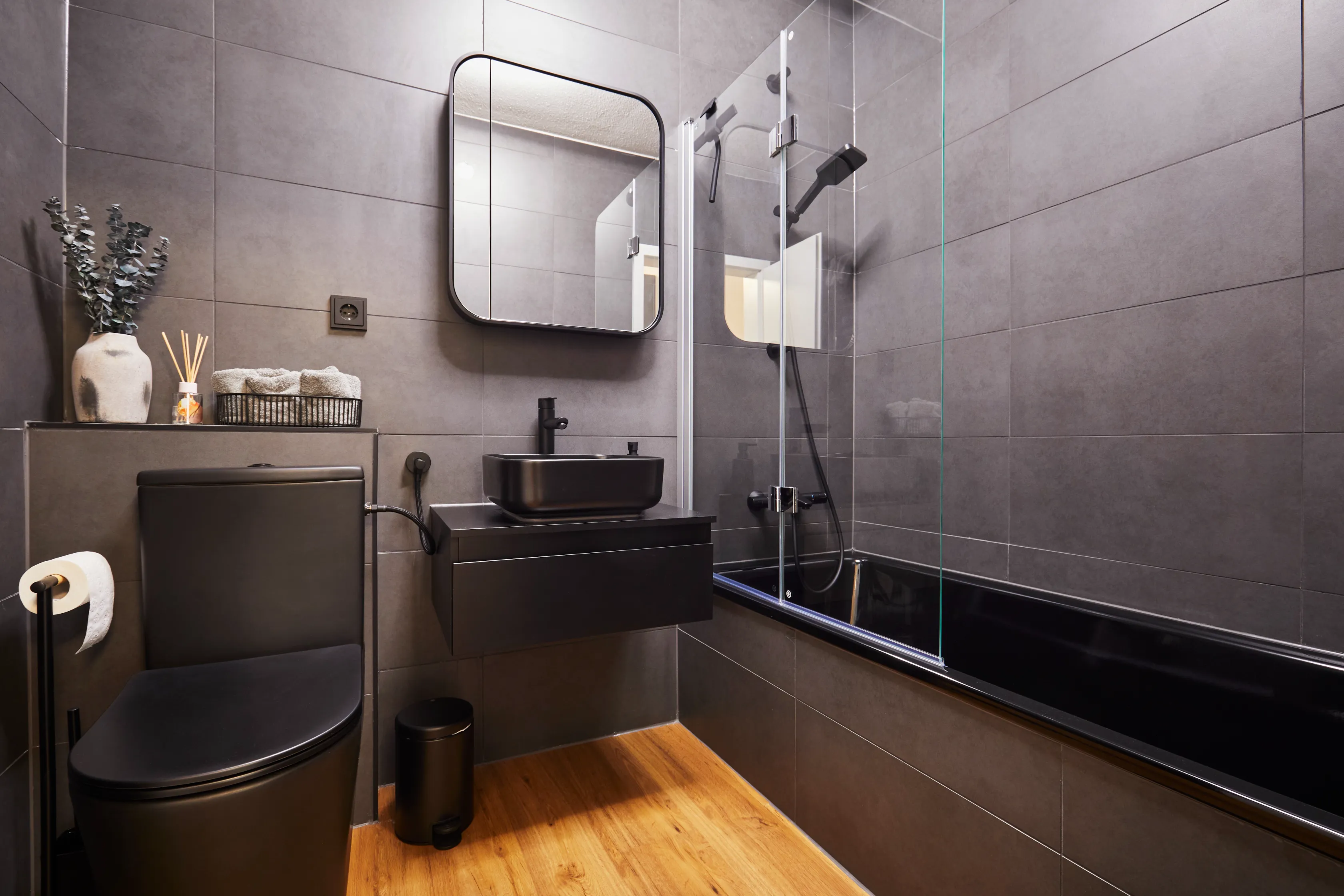 Elegantes Bad mit dunklen Fliesen, schwarzen Armaturen und Wanne