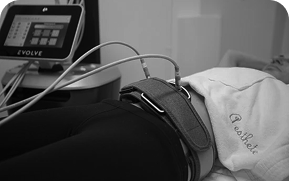 Person lying down with a medical or fitness device attached around the abdomen connected to a monitor labeled EVOLVE.