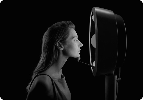 Profile of a woman facing a black device with circular lights in a dark setting.