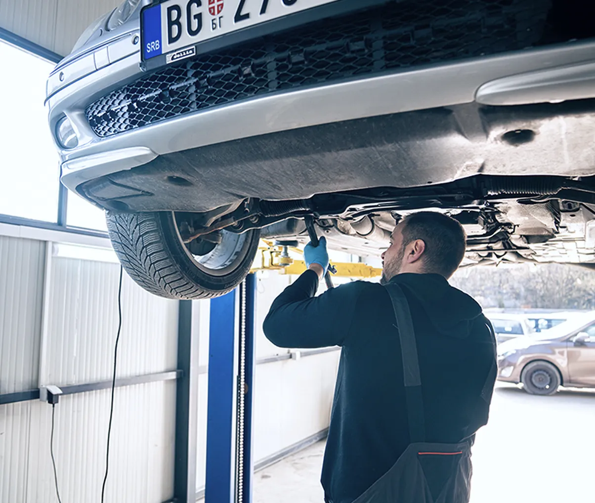 Mehaničar pregleda donji deo vozila - bezbednosni pregled i priprema za tehnički.