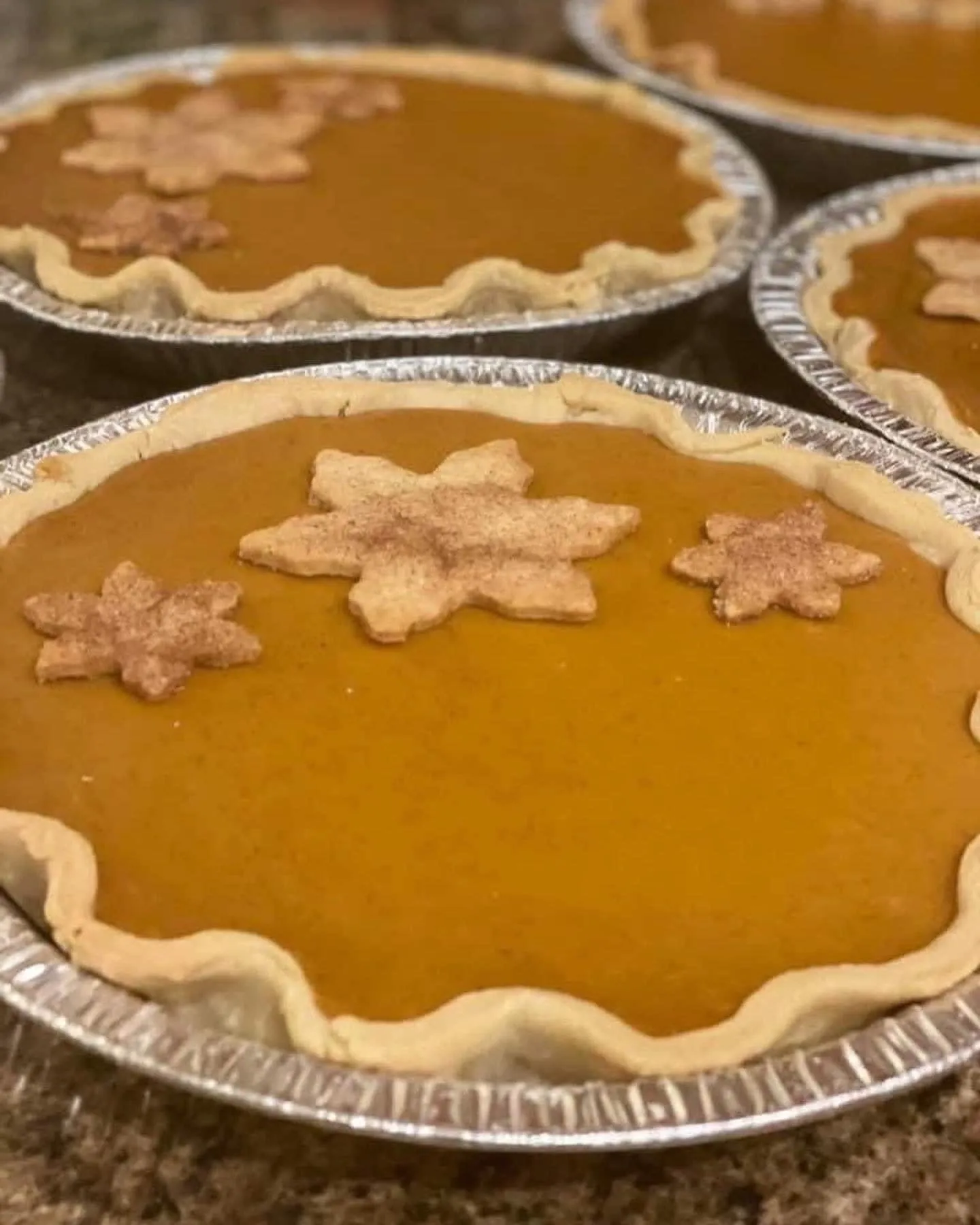 Close-up of several pumpkin pies with decorative star-shaped crust cutouts on top.