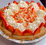 Strawberry cream pie topped with whipped cream and sliced strawberries in a foil pie dish.