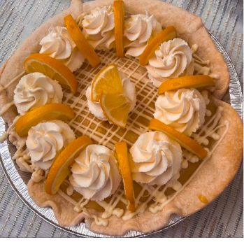 Cream pie topped with whipped cream swirls and orange slices on a lattice drizzle.