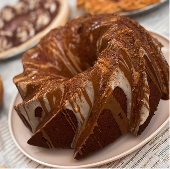 Bundt cake with caramel and white icing drizzled on top, served on a white plate.