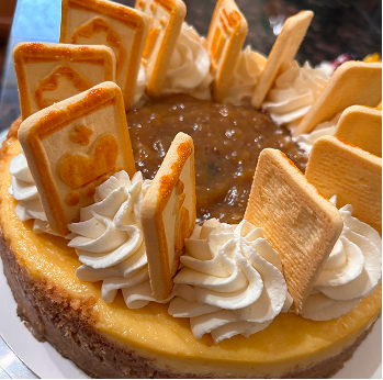 Cheesecake topped with whipped cream swirls and rectangular cookies arranged around the edge with caramel filling in the center.