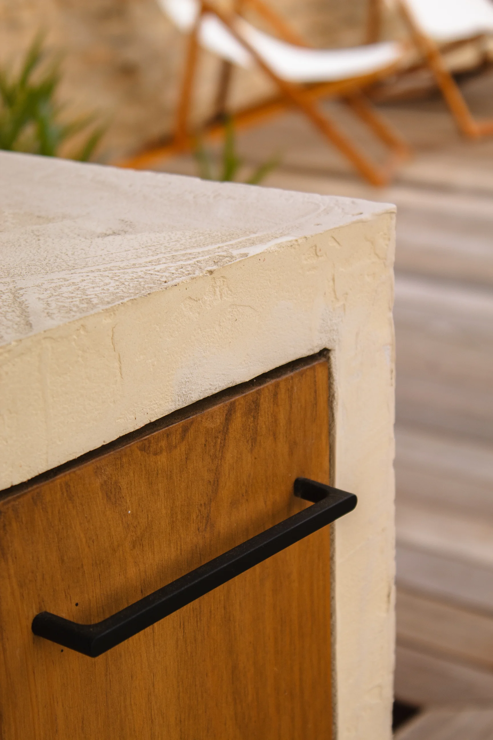 Gros plan sur une porte d'armoire en bois avec une poignée noire dans un décor extérieur.