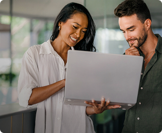 Zwei Kollegen lächeln während sie auf einen Laptop schauen