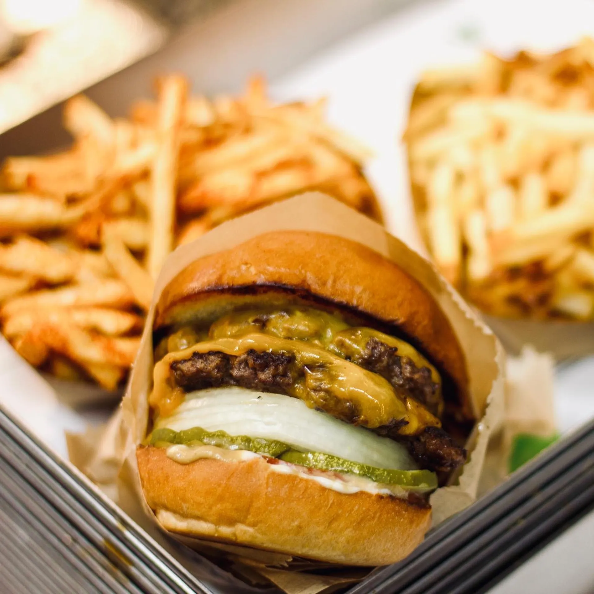 Close-up of a juicy cheeseburger with pickles and onions, paired with crispy golden fries.