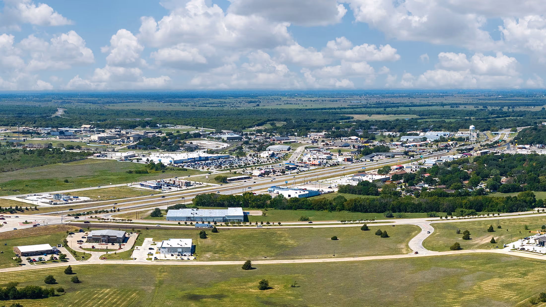 Aerial view of a suburban neighborhood next to a construction site and green forested area.