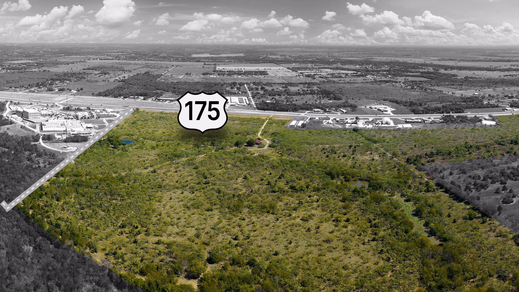 Aerial view of green land near highway 175 with some scattered buildings and cloudy sky.