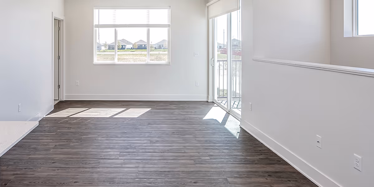 Empty living room with wood flooring and windows