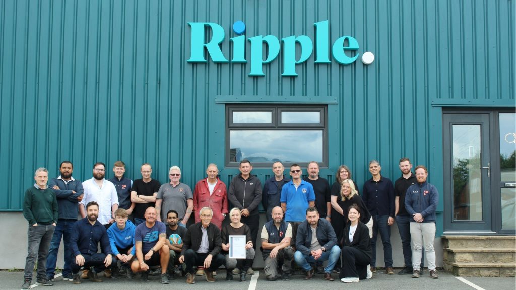 The full Ripple team gathered outside their headquarters, proudly posing with their certification plaque under the company sign.