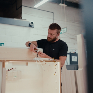 Craftsperson assembling bespoke paint display unit in workshop.