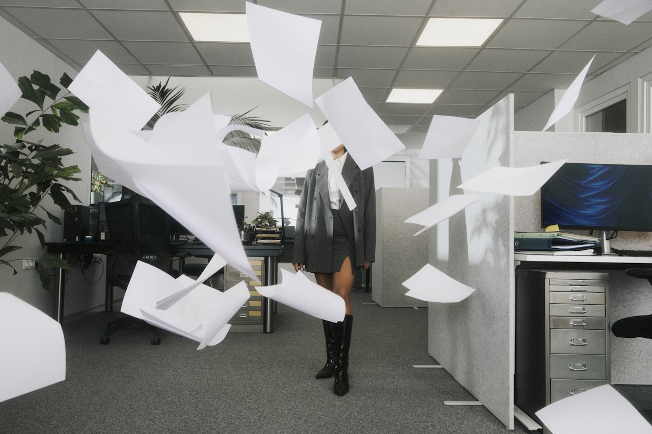Person walking in an office with papers flying around them.