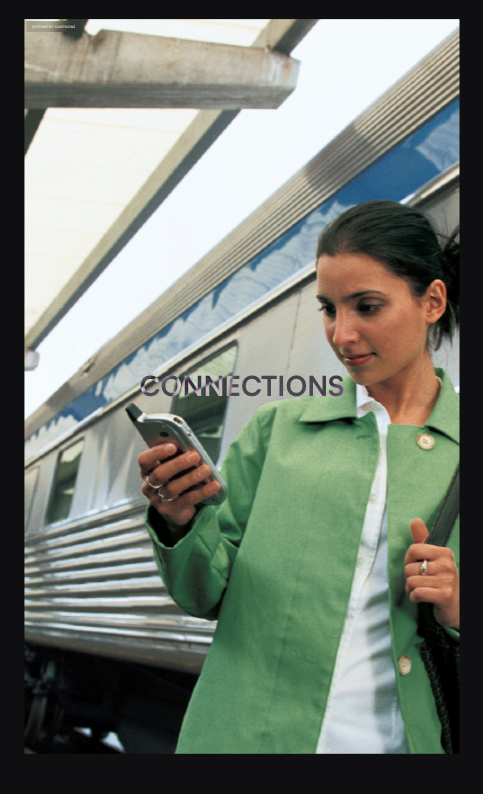 Woman in green coat looking at her smartphone while standing next to a train.