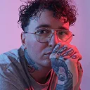 Man wearing glasses with neon pink and blue lighting effect against dark background