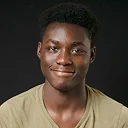 Young man with dark skin wearing beige t-shirt posing against dark background