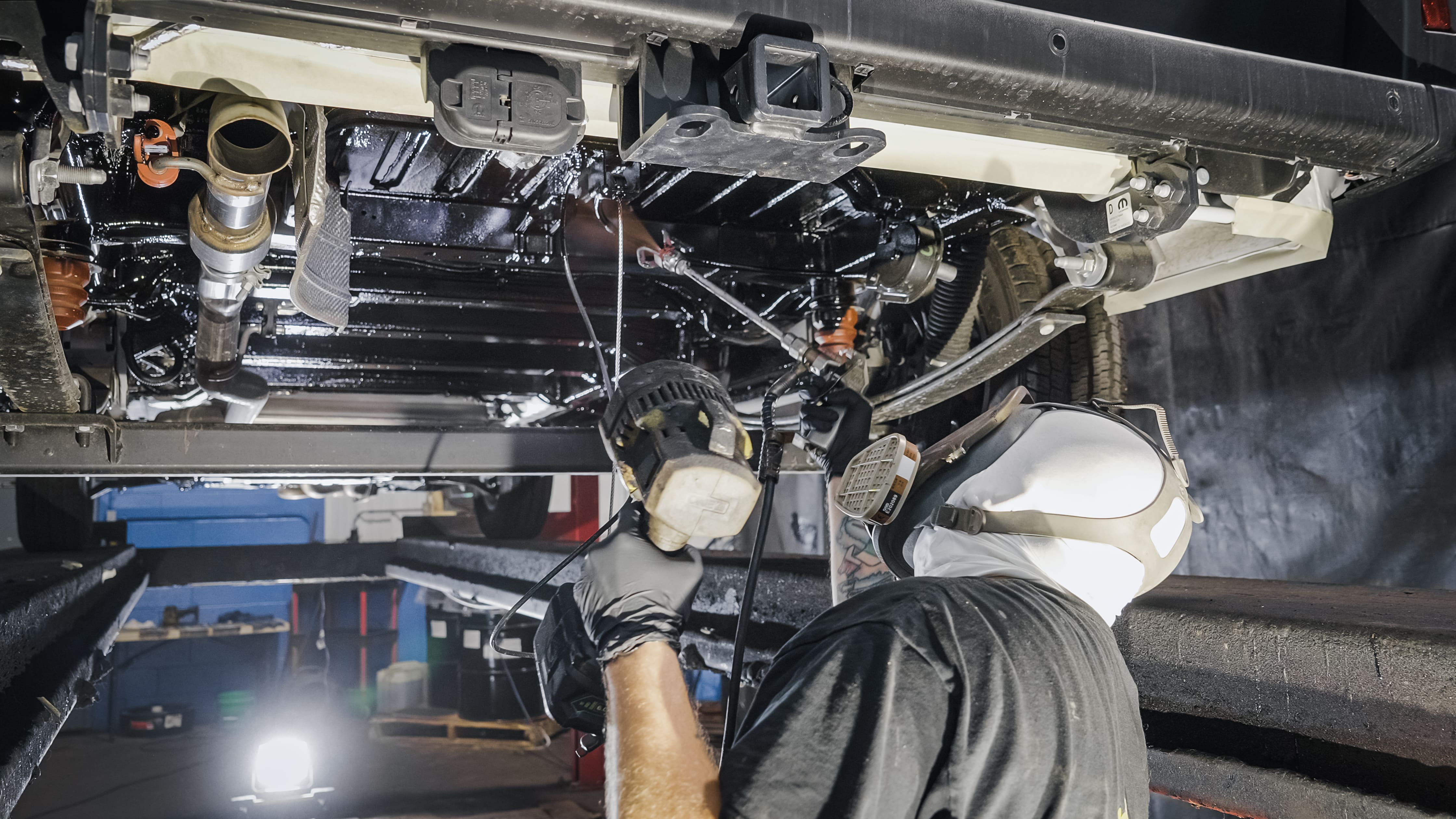 Vehicle undercarriage being treated with professional rustproofing spray by Madison Auto Trim, Wisconsin. Vehicle corrosion protection, anti-rust undercoating, and preventive rustproof services.