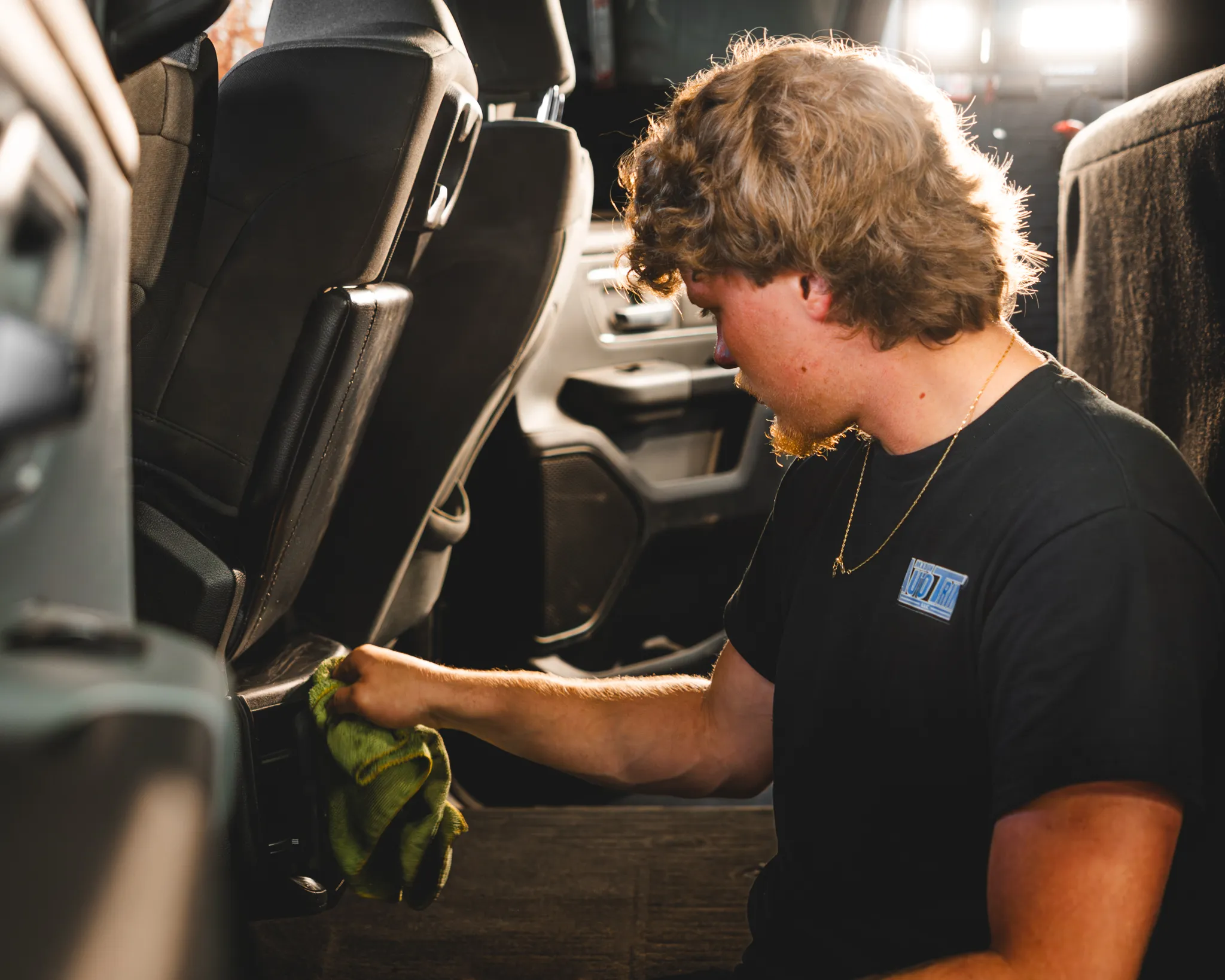 Photo of a man in a black shirt wiping down the interior of a pickup truck during a automotive detail at Madison Auto Trim