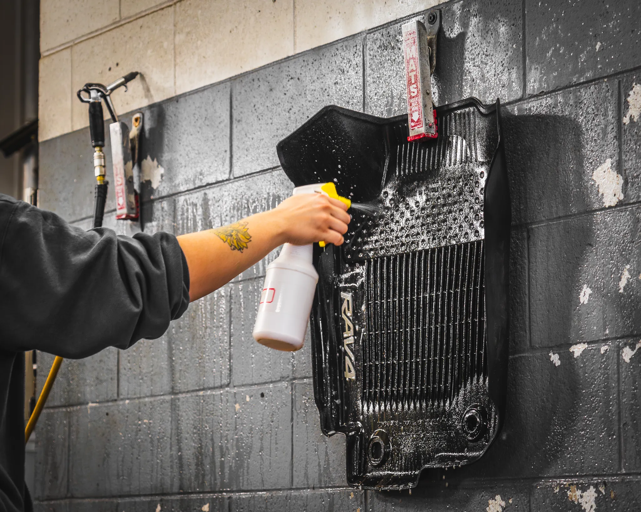 Photo of a worker spraying cleaning chemicals on a Toyota RAV4 floor mat during a full-service automotive detail from Madison Auto Trim, Wisconsin