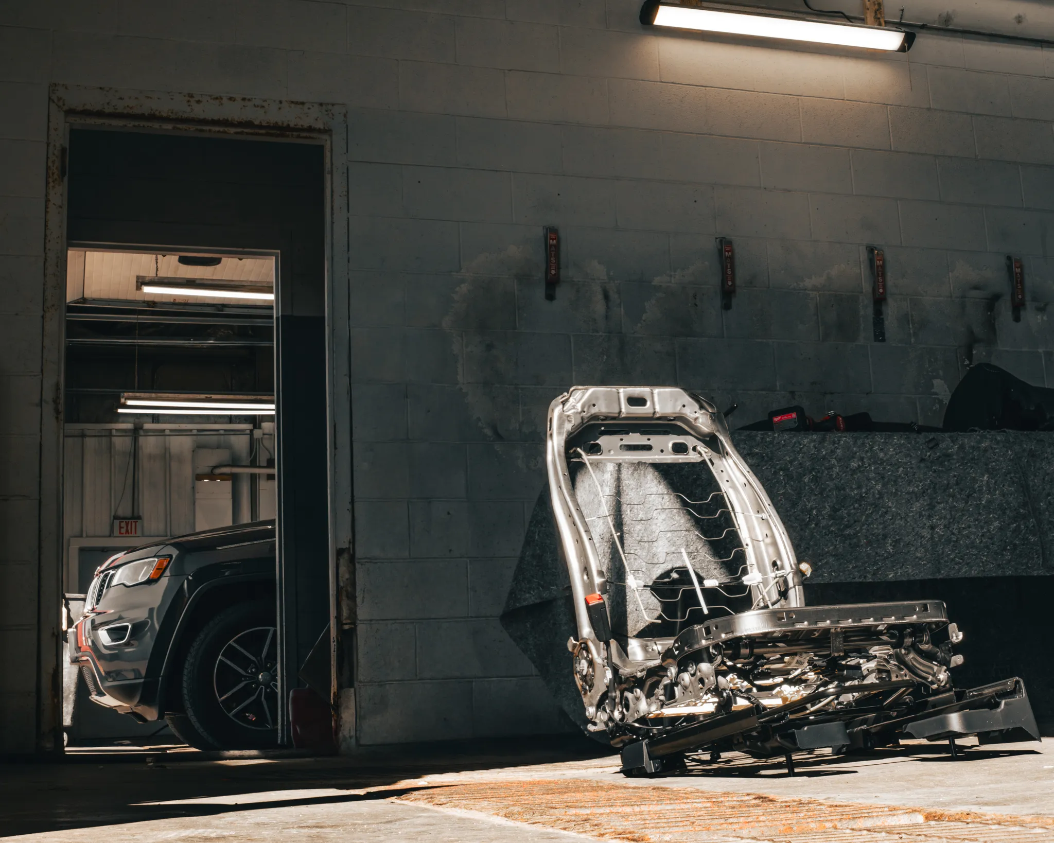 Photo of a stripped car seat, likely from the front row, waiting to be worked on while sitting next to a detailing bay in Madison Auto Trim.