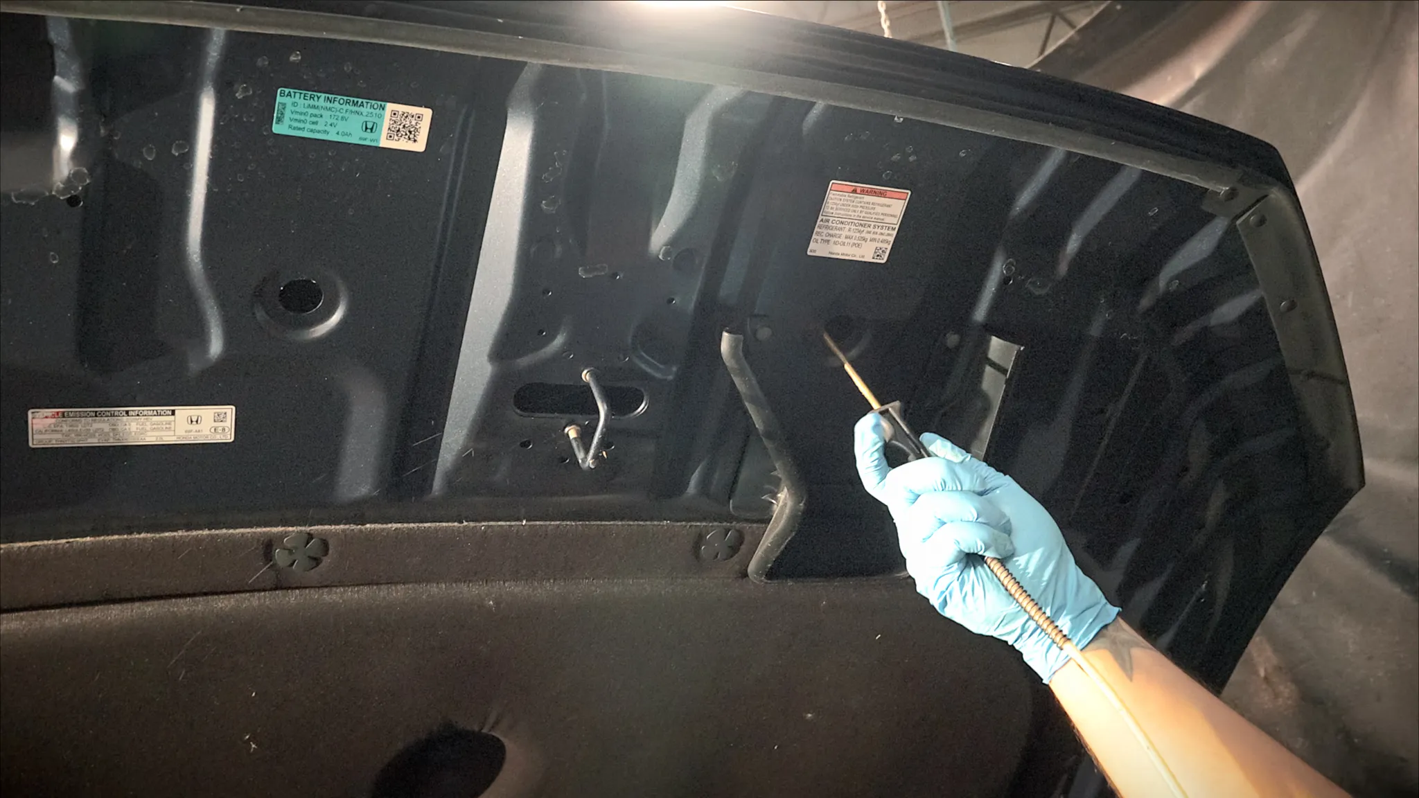 Sedan inner hood being treated with professional rustproofing spray by Madison Auto Trim, Wisconsin. Vehicle corrosion protection, anti-rust undercoating, and preventive rustproof services.