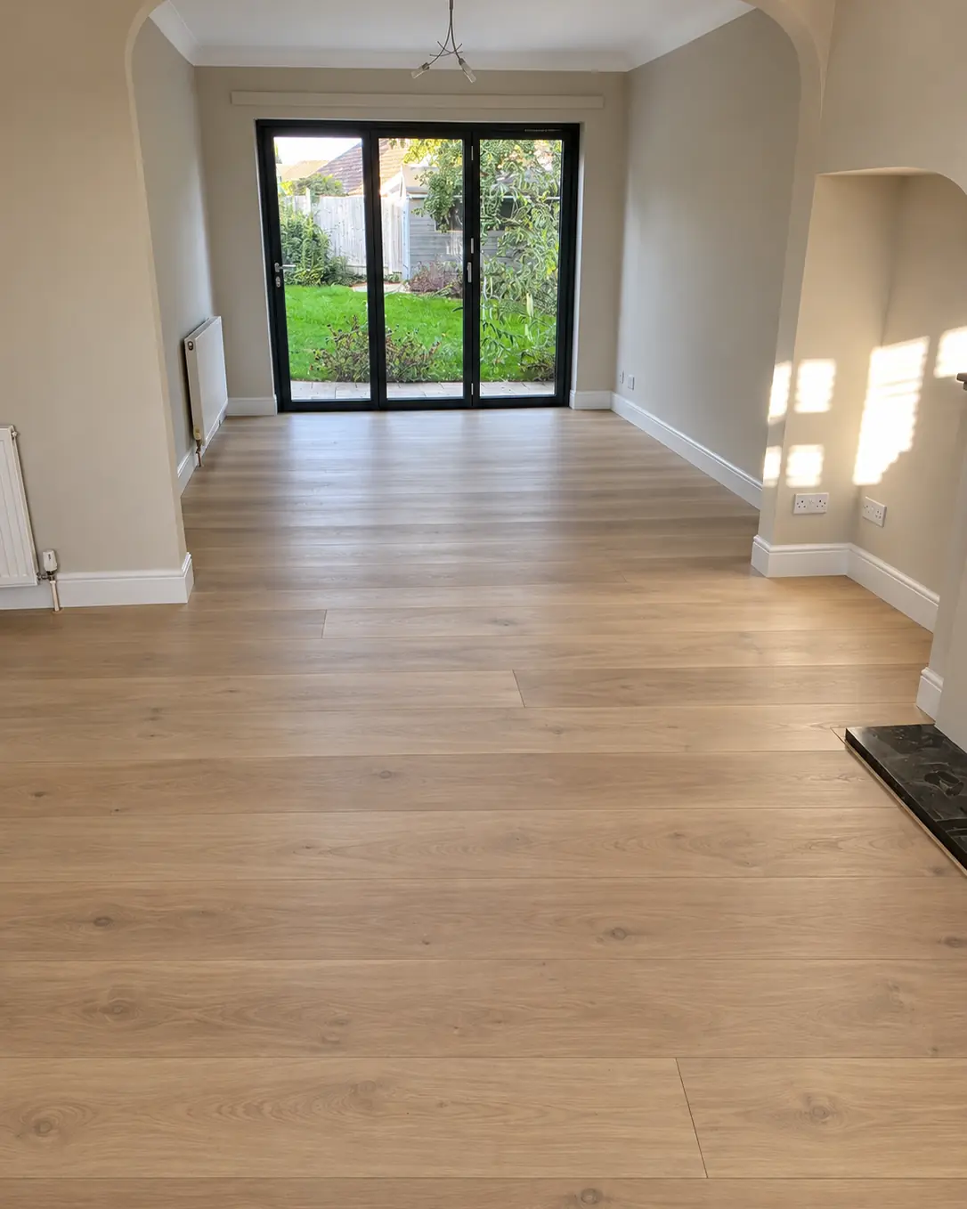 Wide-plank engineered oak flooring in a living room with bi-fold doors to the garden
