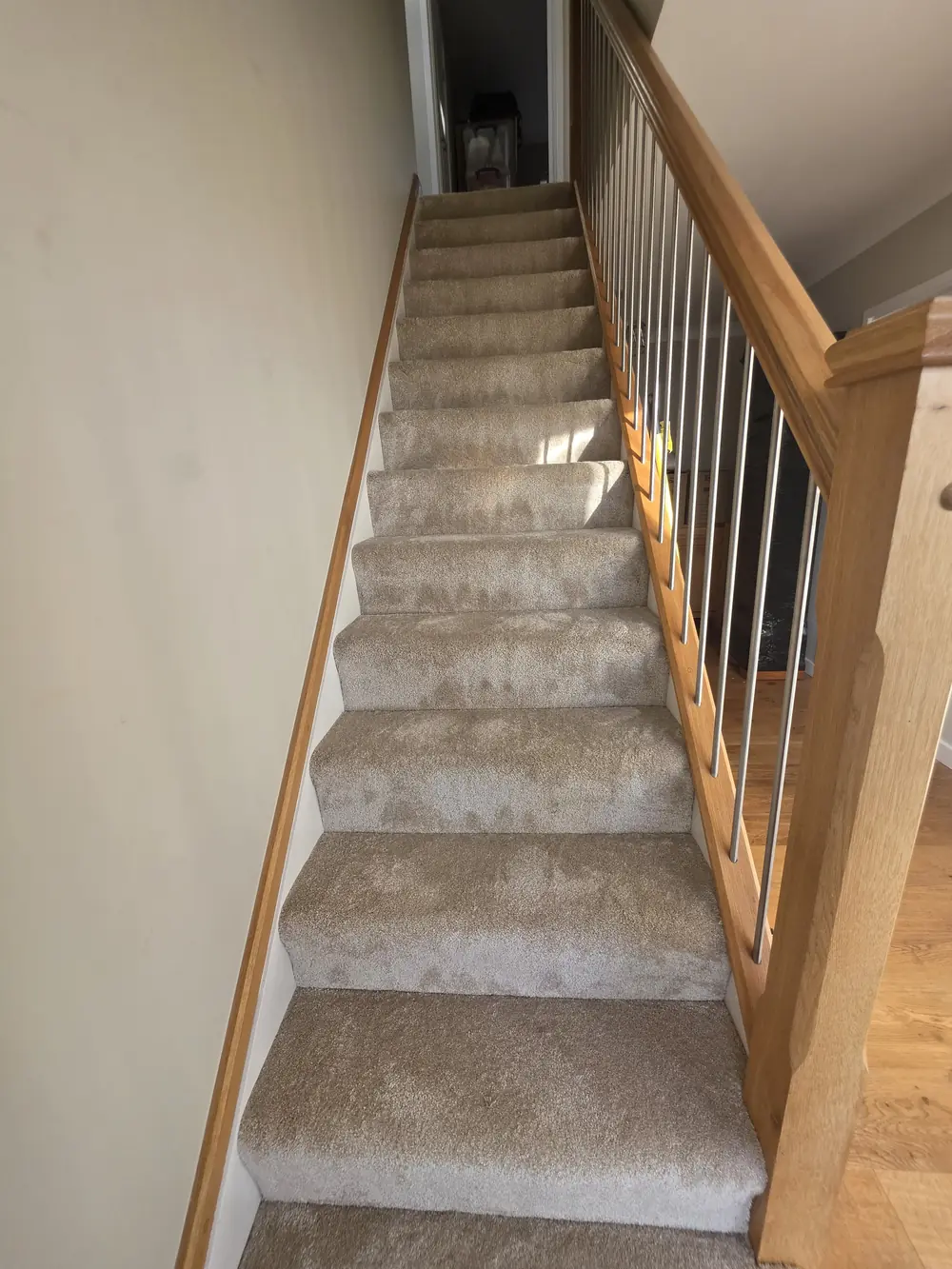 Cream carpet fitted to a staircase with oak handrail and black spindles