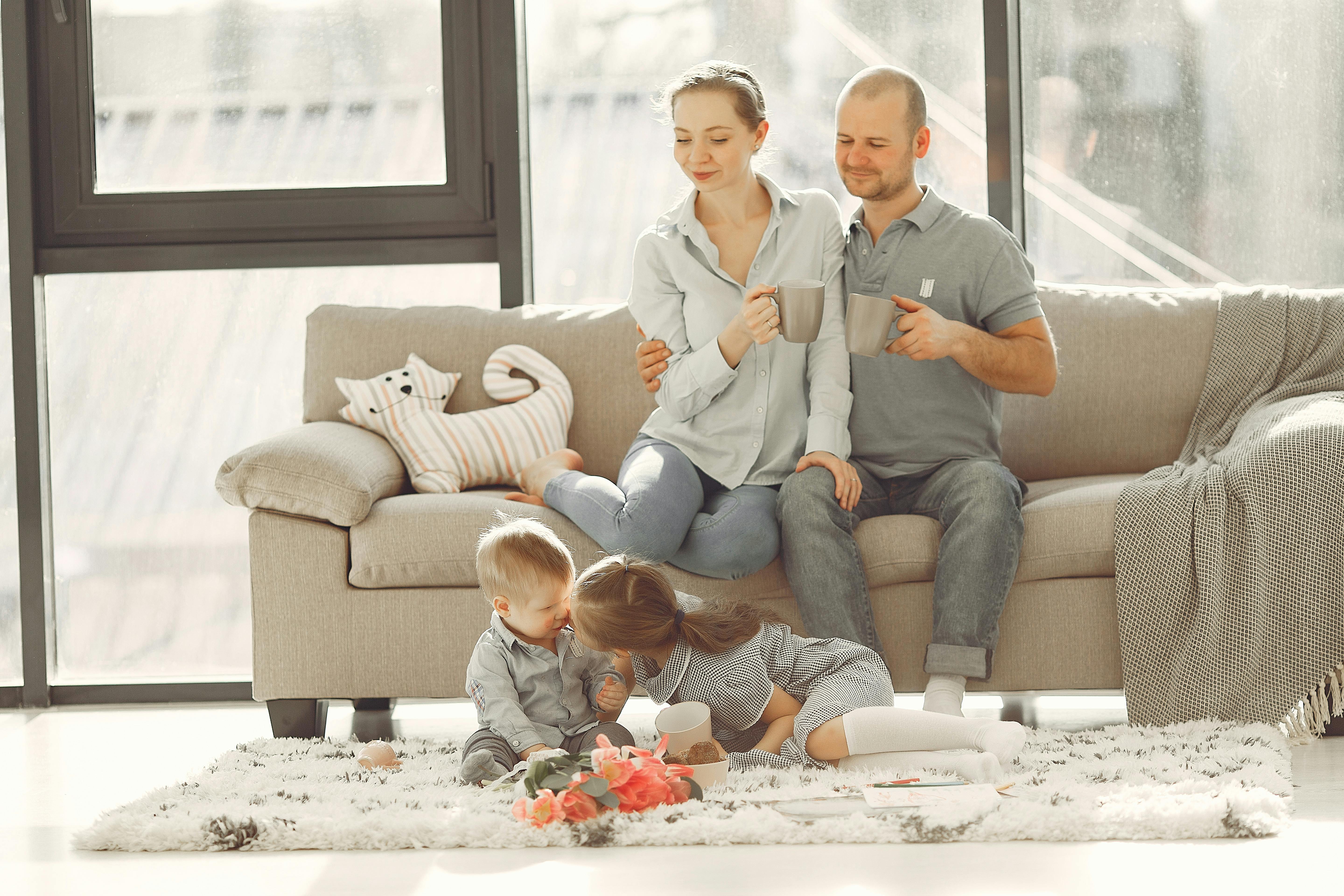 Family with children relaxing on carpet in a cozy living room — professional carpet fitting in Peterborough, Cambridgeshire by Cambridgeshire Carpets