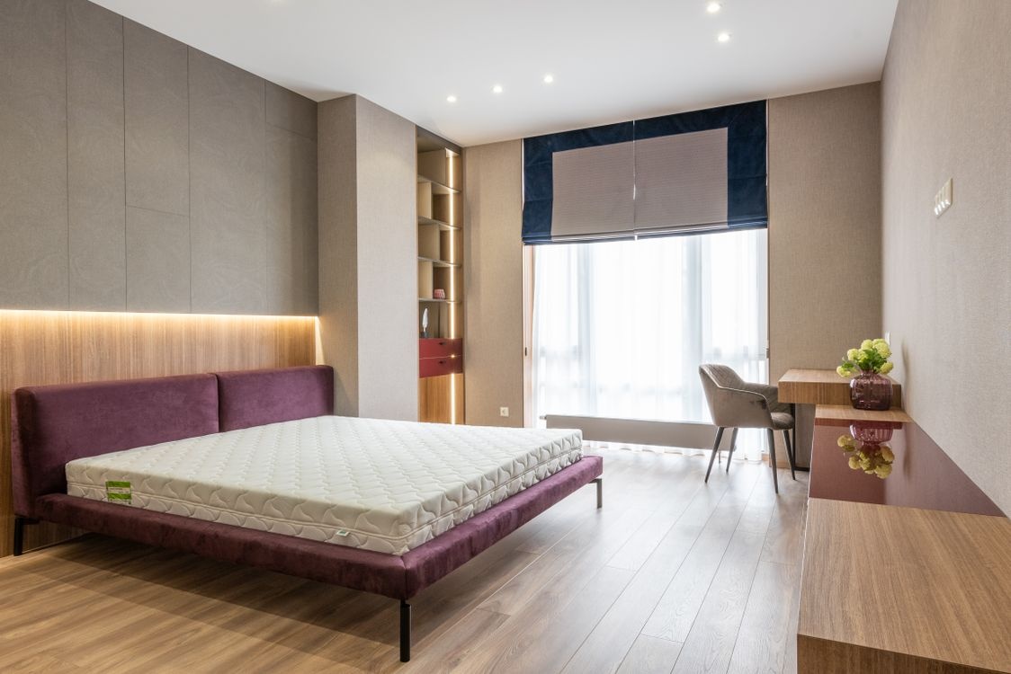 Quiet luxury bedroom with warm natural oak LVT flooring in Peterborough — understated neutral interior design by Cambridgeshire Carpets