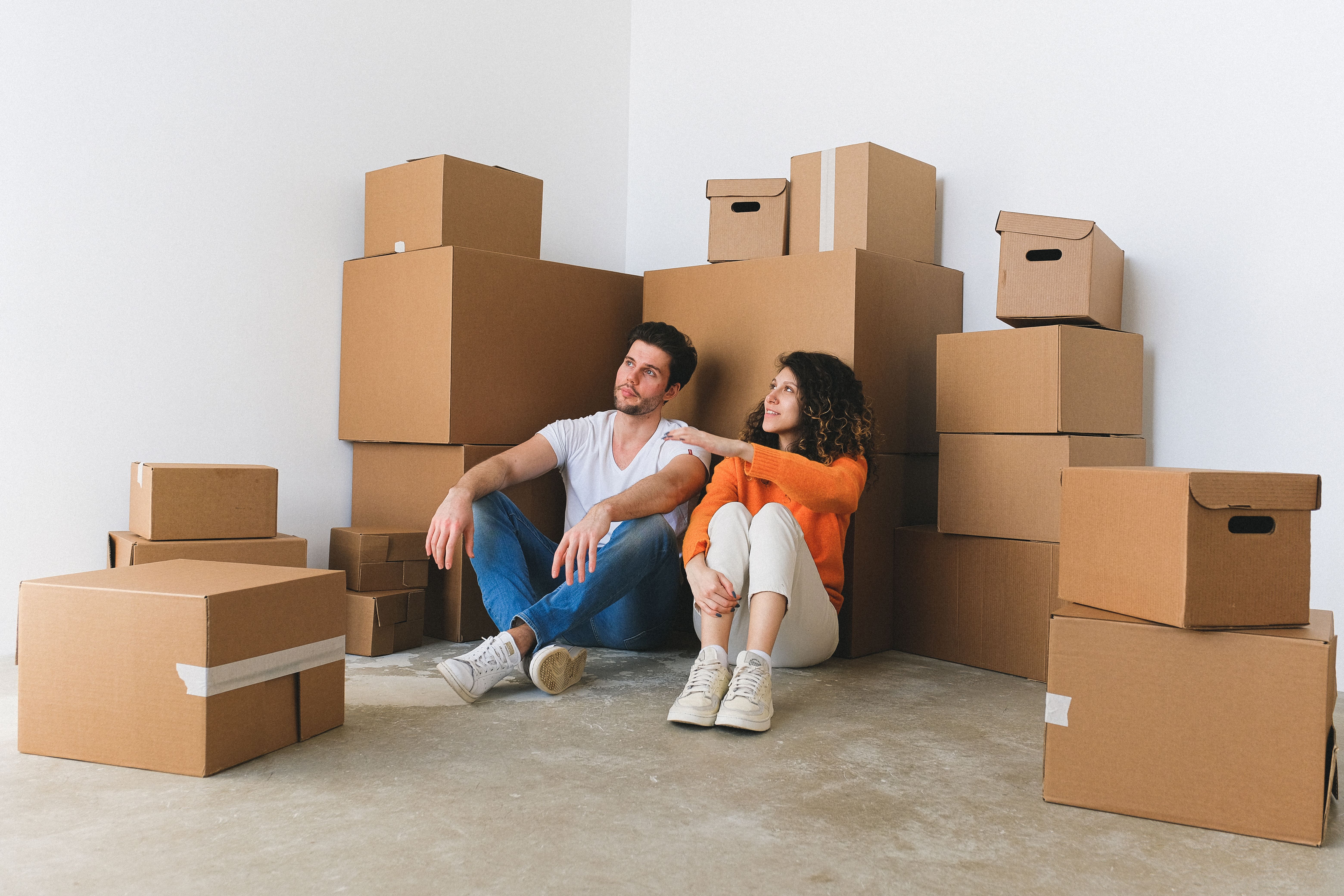 First-time buyers sitting on a bare floor with moving boxes in a new home in Peterborough, PE1–PE7 — Cambridgeshire Carpets