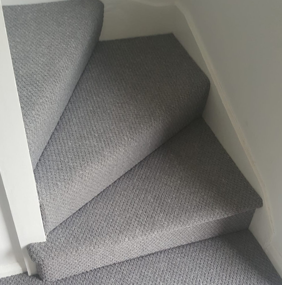 Close-up of carpeted staircase with grey textured carpet on each step in Peterborough.