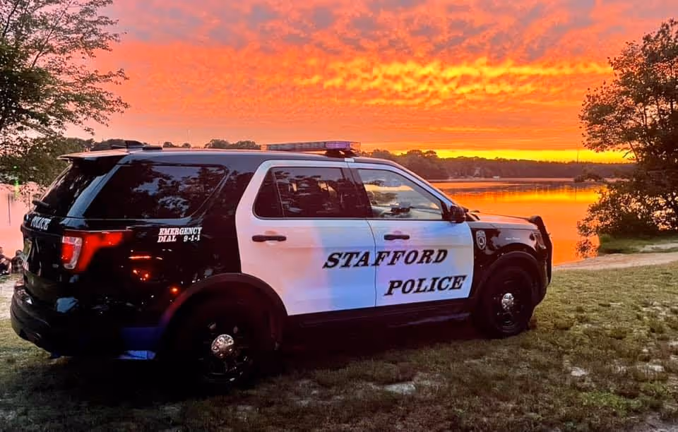 Stafford Township Police vehicle parked near a lake during a vibrant sunset.