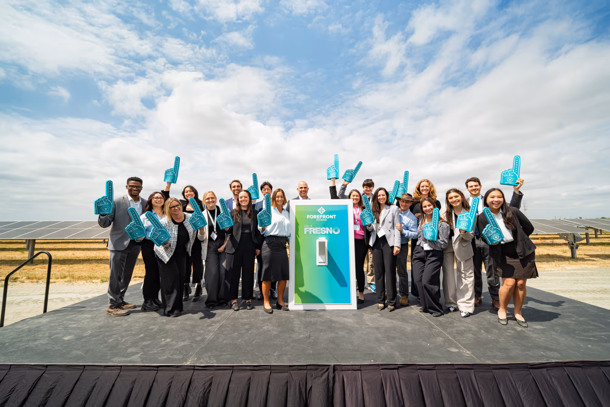 Group of people on stage with foam fingers around a large switch display labeled ForeFront Power and City of Fresno.