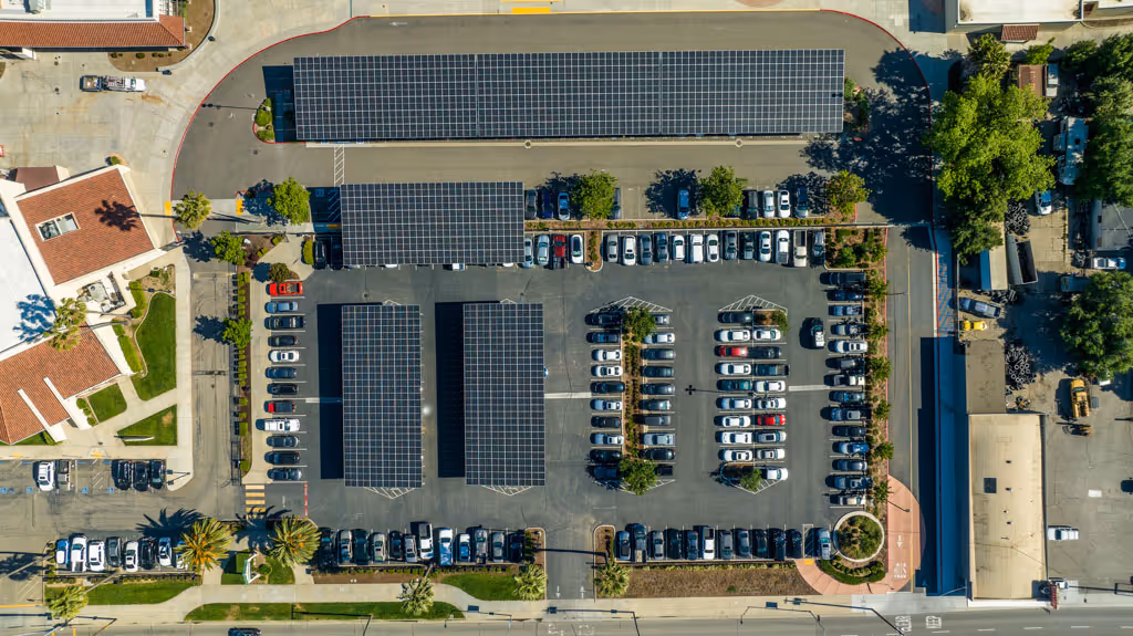 Aerial view of a parking lot with solar panel canopies and numerous parked cars in daytime.