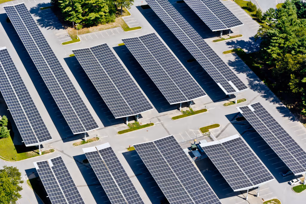 Aerial view of parking lot with rows of solar panels mounted above parking spaces.