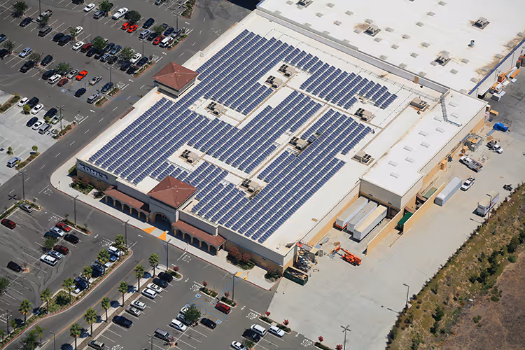 Aerial view of a large retail building with solar panels installed fully on its rooftop.