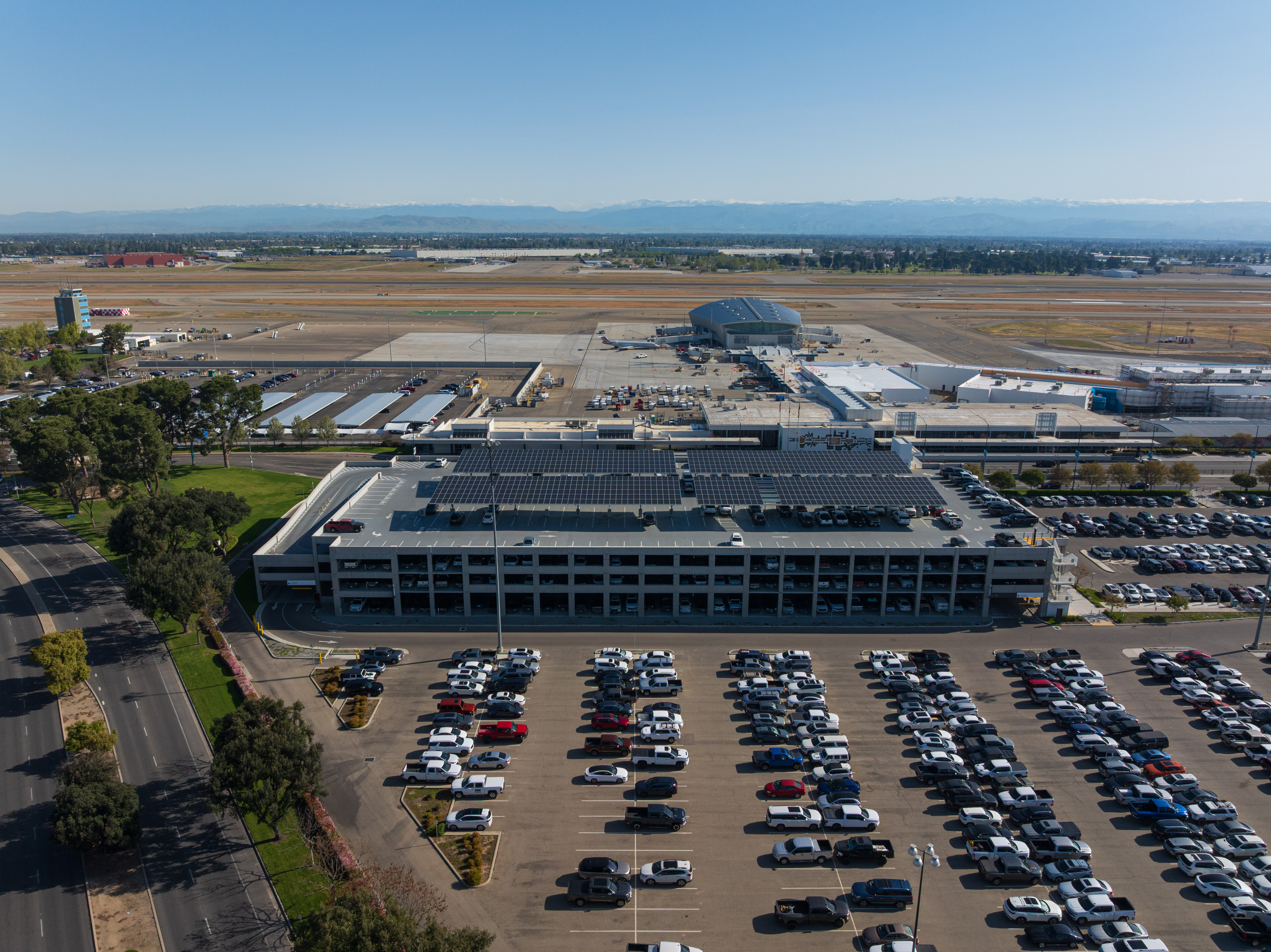 Aerial view of airport parking garage with solar panels on the roof and cars in the parking lot.
