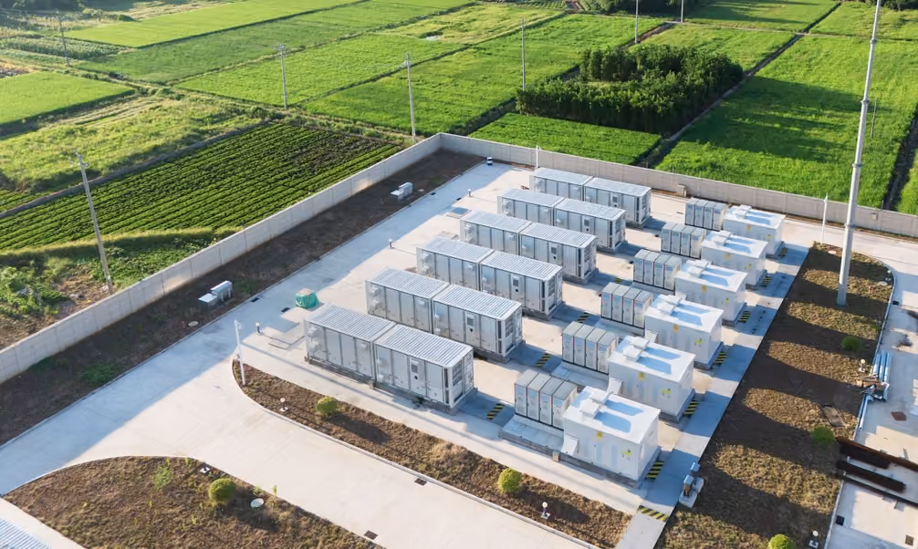 Aerial view of an outdoor electrical substation surrounded by green agricultural fields.